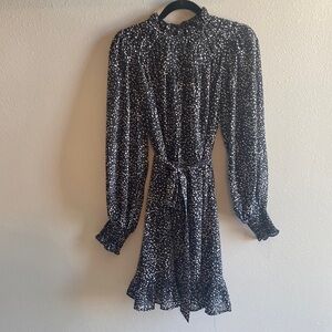 Black patterned dress with high neck ruffle. Hemline sits just above the knee.
